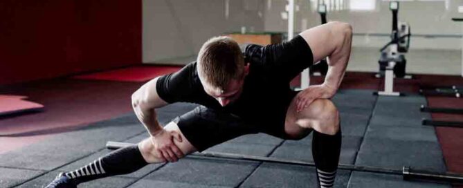 Young man preparing muscles before training. Muscular athlete exercising. Fit man stretching. Professional sportsman warming-up